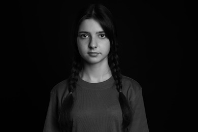 Photo of Portrait of teenage girl on dark background. Black and white effect