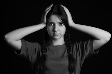 Portrait of teenage girl on dark background. Black and white effect