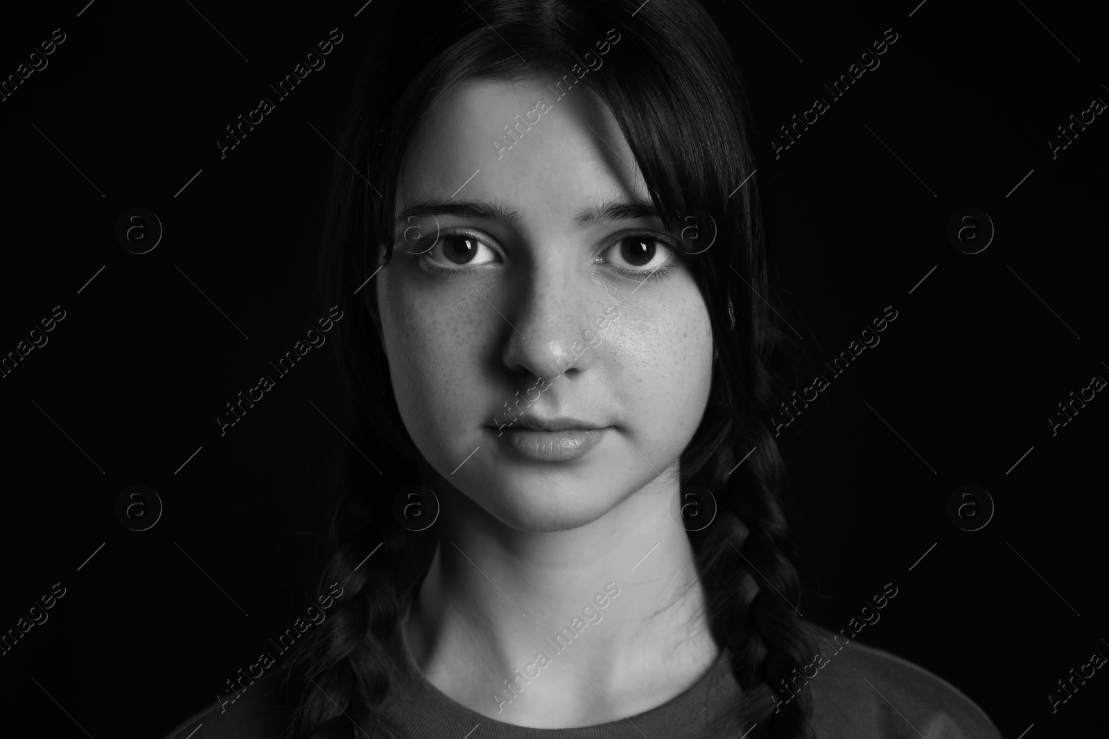 Photo of Portrait of teenage girl on dark background. Black and white effect