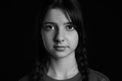 Portrait of teenage girl on dark background. Black and white effect