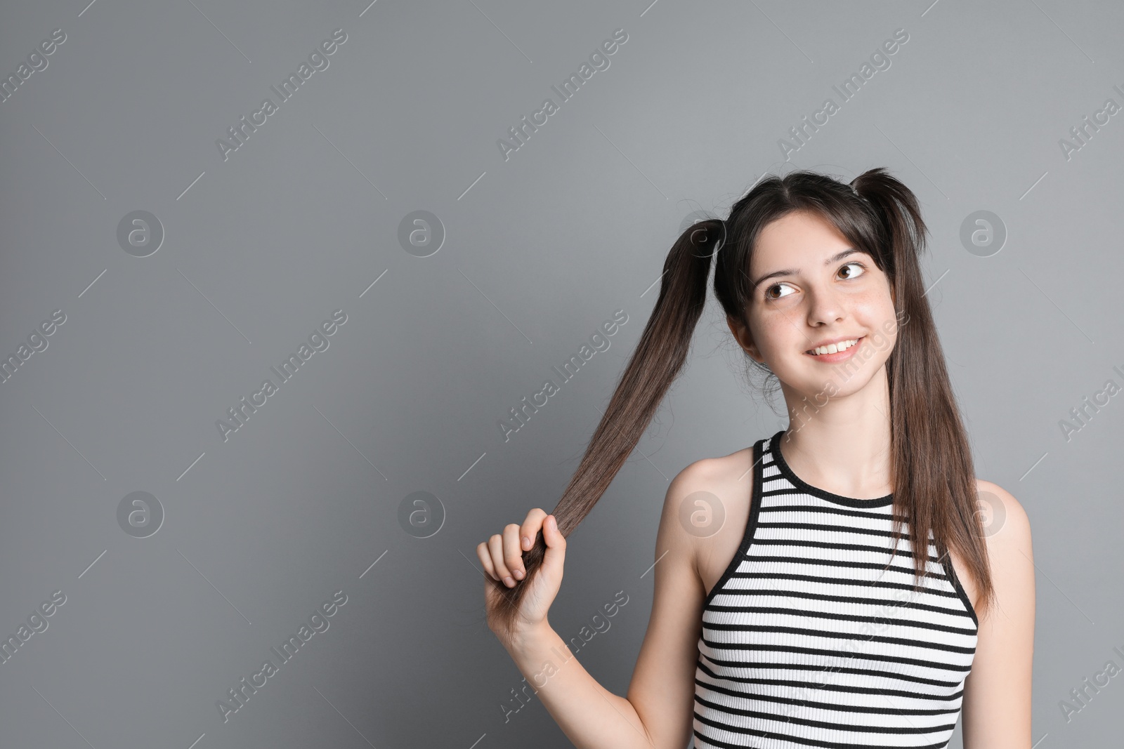 Photo of Portrait of smiling teenage girl on grey background. Space for text