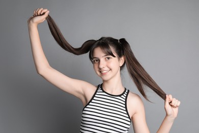 Portrait of smiling teenage girl on grey background