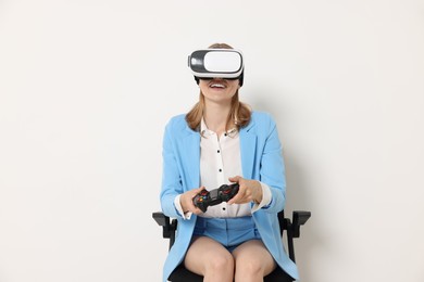 Happy woman with virtual reality headset sitting on chair against white background