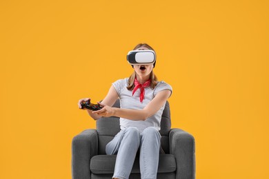 Photo of Emotional woman with virtual reality headset and controller sitting in armchair on yellow background