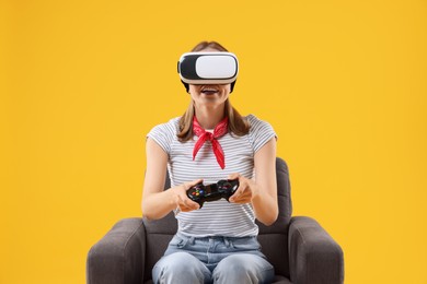 Photo of Surprised woman with virtual reality headset and controller sitting in armchair on yellow background