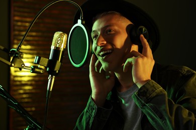 Vocalist with headphones singing into microphone in professional record studio