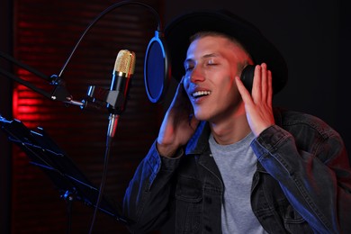 Vocalist with headphones singing into microphone in professional record studio