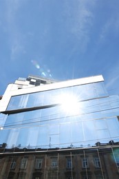 Beautiful building with many windows under blue sky, low angle view