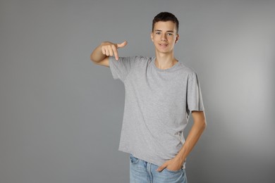 Teenage boy wearing t-shirt on grey background, space for text