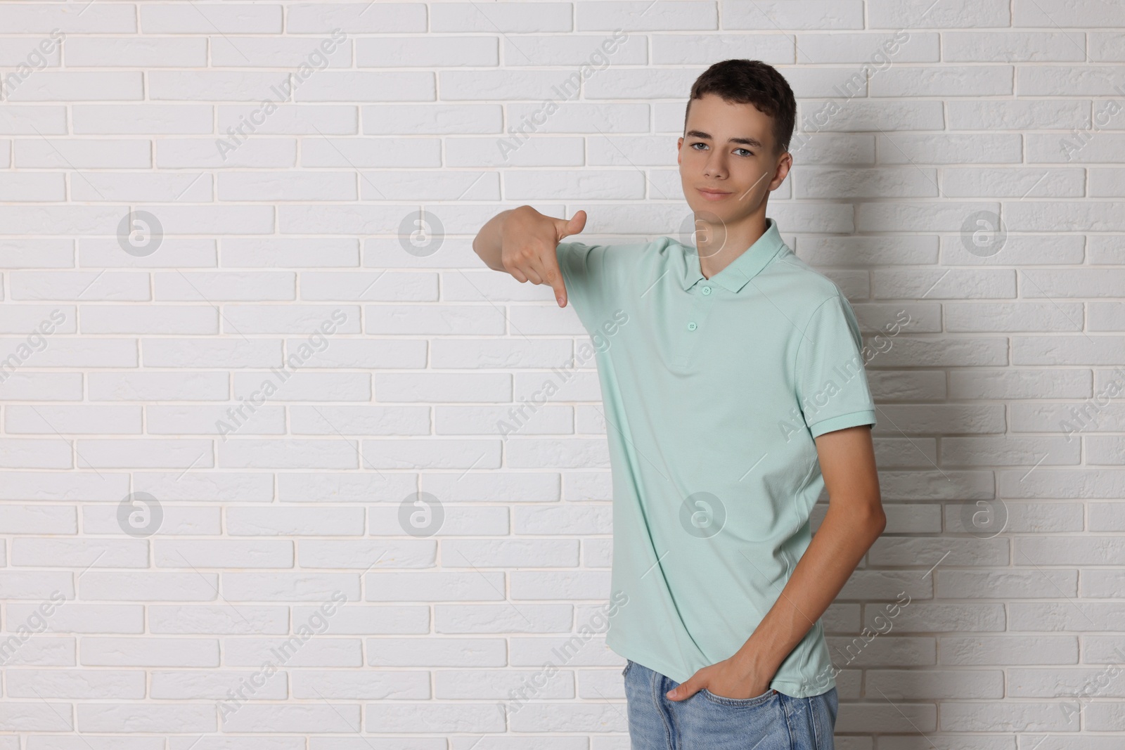 Photo of Teenage boy wearing light green t-shirt near white brick wall, space for text