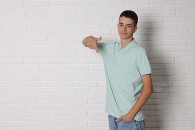 Photo of Teenage boy wearing light green t-shirt near white brick wall, space for text