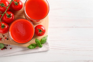 Photo of Tasty tomato juice in glasses with fresh vegetables and spices on white wooden table, flat lay. Space for text