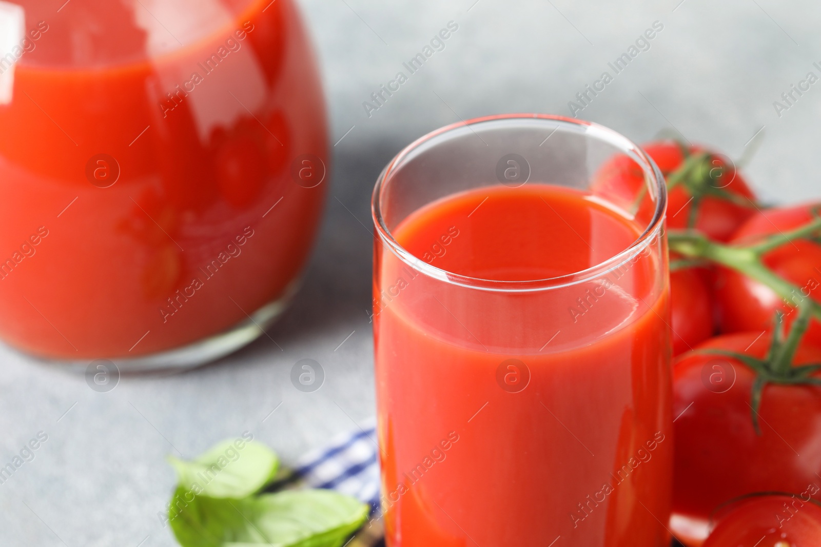 Photo of Fresh tomato juice on light grey table, closeup