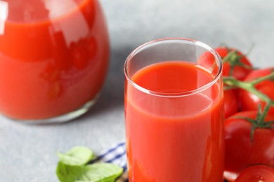 Fresh tomato juice on light grey table, closeup