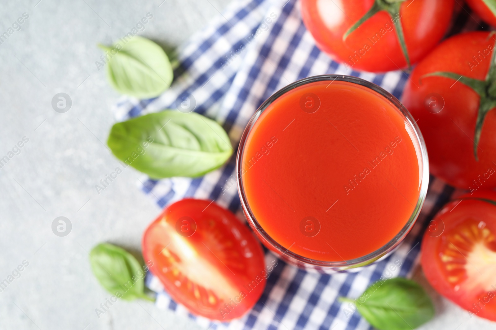 Photo of Fresh tomato juice in glass on light table, top view. Space for text