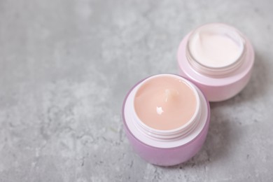 Photo of Jars of creams on gray table. Space for text