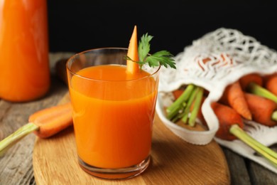 Healthy juice in glass and fresh carrot on wooden table