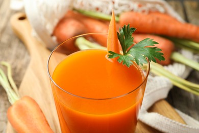 Healthy juice in glass and fresh carrot on wooden table, closeup