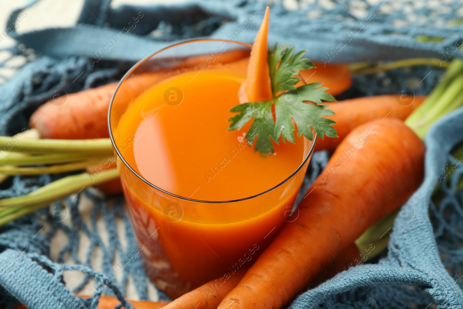 Photo of Healthy juice in glass and fresh carrot on table, closeup