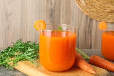 Photo of Healthy carrot juice in glasses and fresh vegetables on wooden table