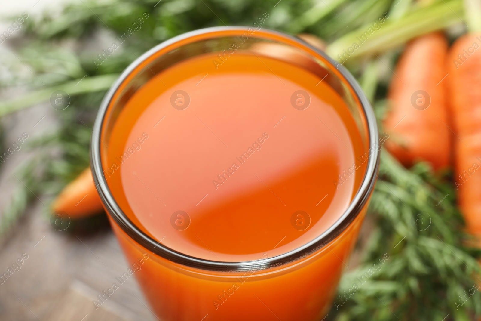 Photo of Healthy carrot juice in glass and fresh vegetables on table, closeup