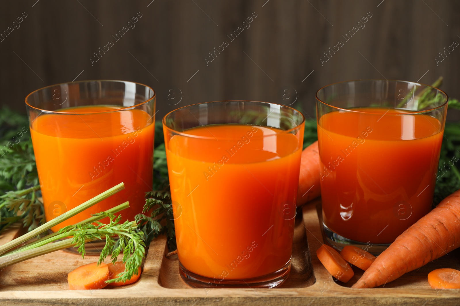 Photo of Healthy carrot juice in glasses and fresh vegetables on table