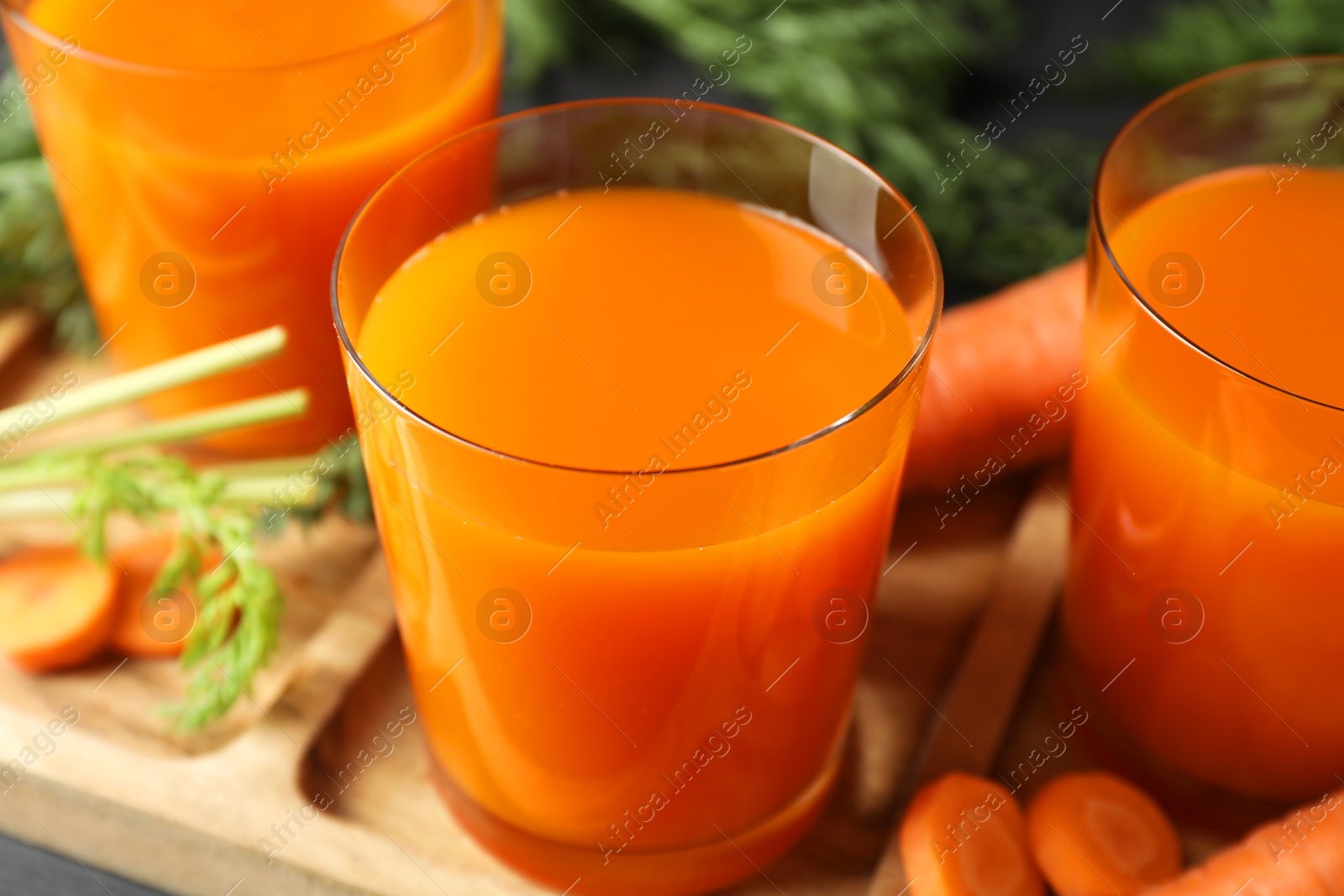 Photo of Healthy carrot juice in glasses and fresh vegetable on table, closeup