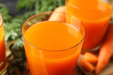 Photo of Healthy carrot juice in glasses and fresh vegetable on table, closeup