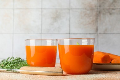 Photo of Healthy carrot juice in glasses, fresh vegetable and knife on color textured table