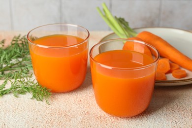 Photo of Healthy carrot juice in glasses and fresh vegetables on color textured table