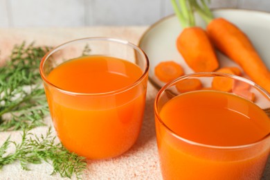 Photo of Healthy carrot juice in glasses and fresh vegetables on color textured table, closeup