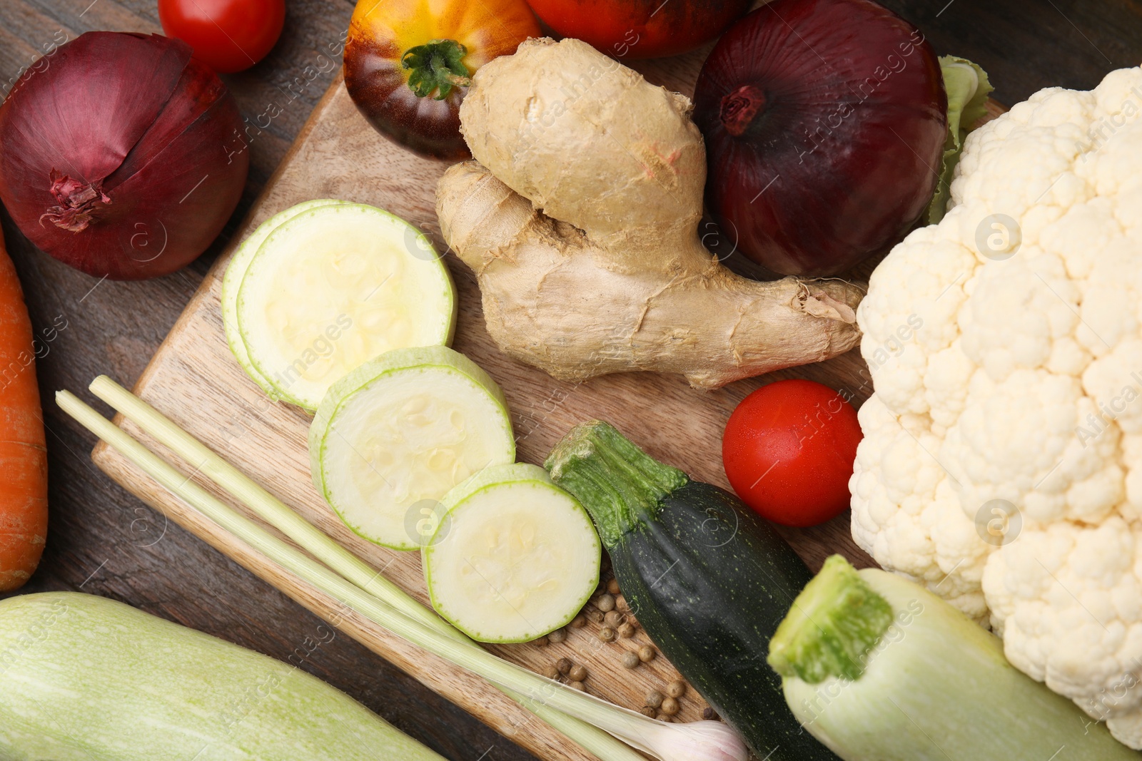 Photo of Cooking tasty stew. Fresh vegetables and peppercorns on wooden table, top view