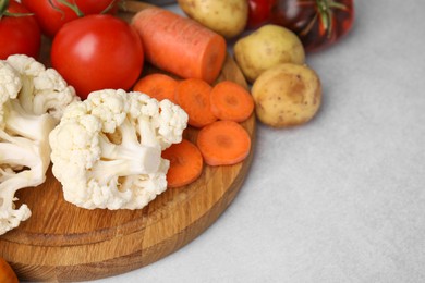 Photo of Cooking vegetable stew. Cauliflower, tomatoes, carrot and potatoes on light grey table, space for text