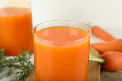 Fresh carrot juice and vegetables on light table, closeup