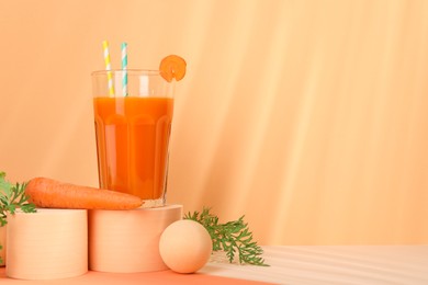 Photo of Fresh carrot juice in glass and vegetable on coral background. Space for text