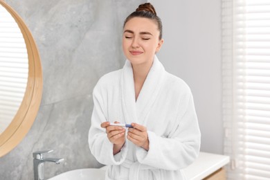 Sad woman holding pregnancy test in bathroom