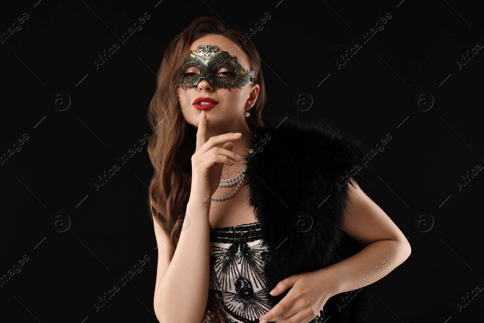 Photo of Beautiful woman wearing carnival mask posing on black background