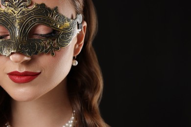 Photo of Beautiful woman wearing carnival mask on black background, closeup. Space for text