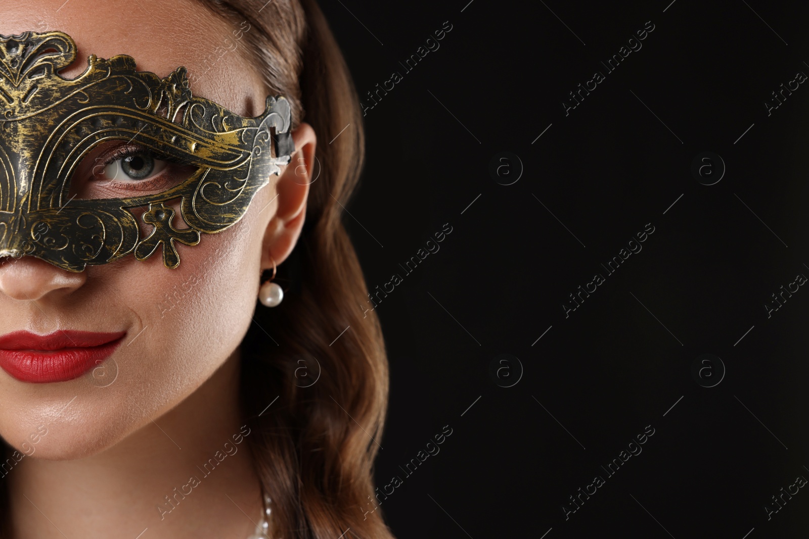 Photo of Beautiful woman wearing carnival mask on black background, closeup. Space for text