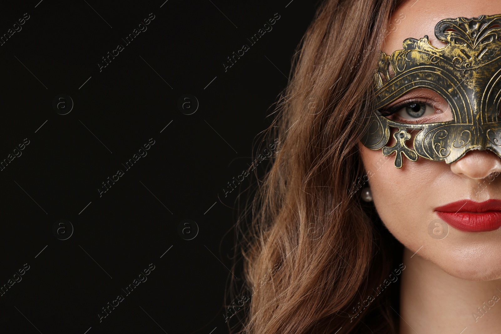 Photo of Beautiful woman wearing carnival mask on black background, closeup. Space for text