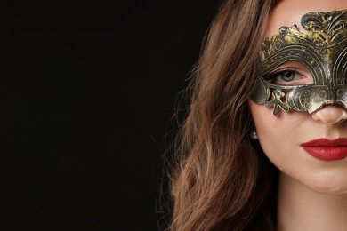 Beautiful woman wearing carnival mask on black background, closeup. Space for text