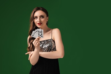 Photo of Poker game. Charming woman with playing cards on green background. Space for text