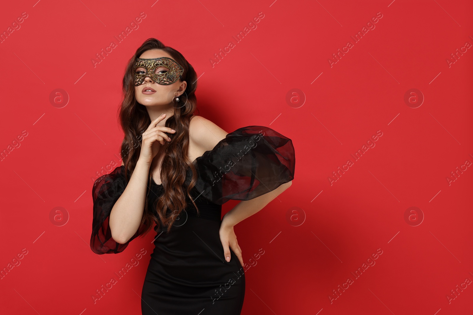 Photo of Beautiful woman wearing carnival mask on red background. Space for text