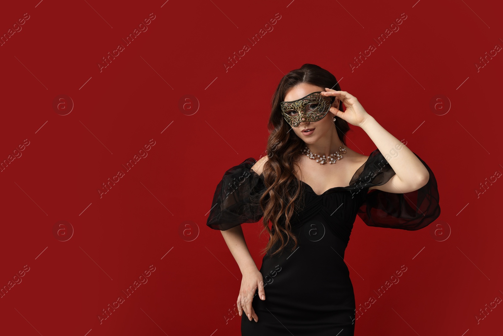 Photo of Beautiful woman wearing carnival mask on red background. Space for text