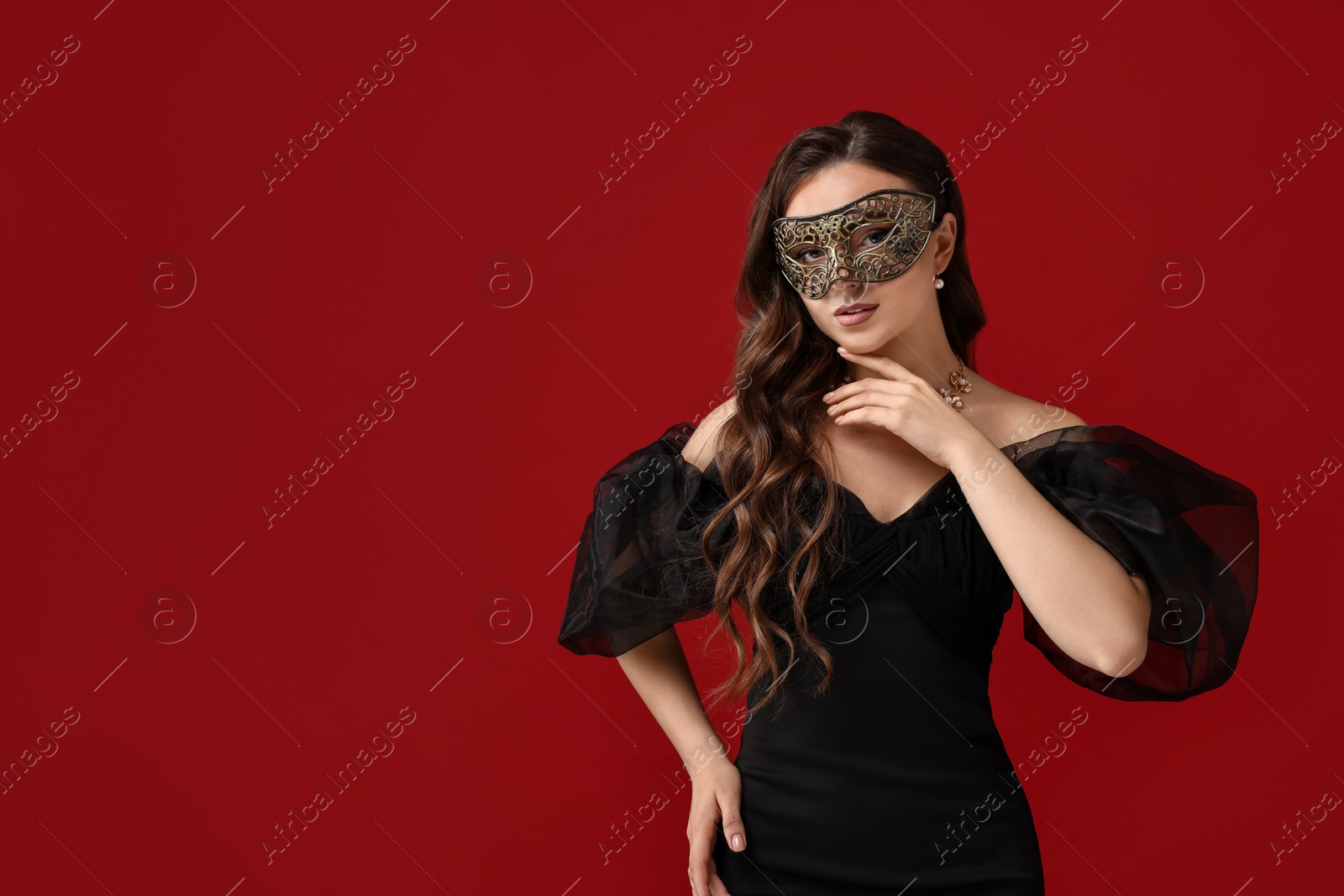 Photo of Beautiful woman wearing carnival mask on red background. Space for text