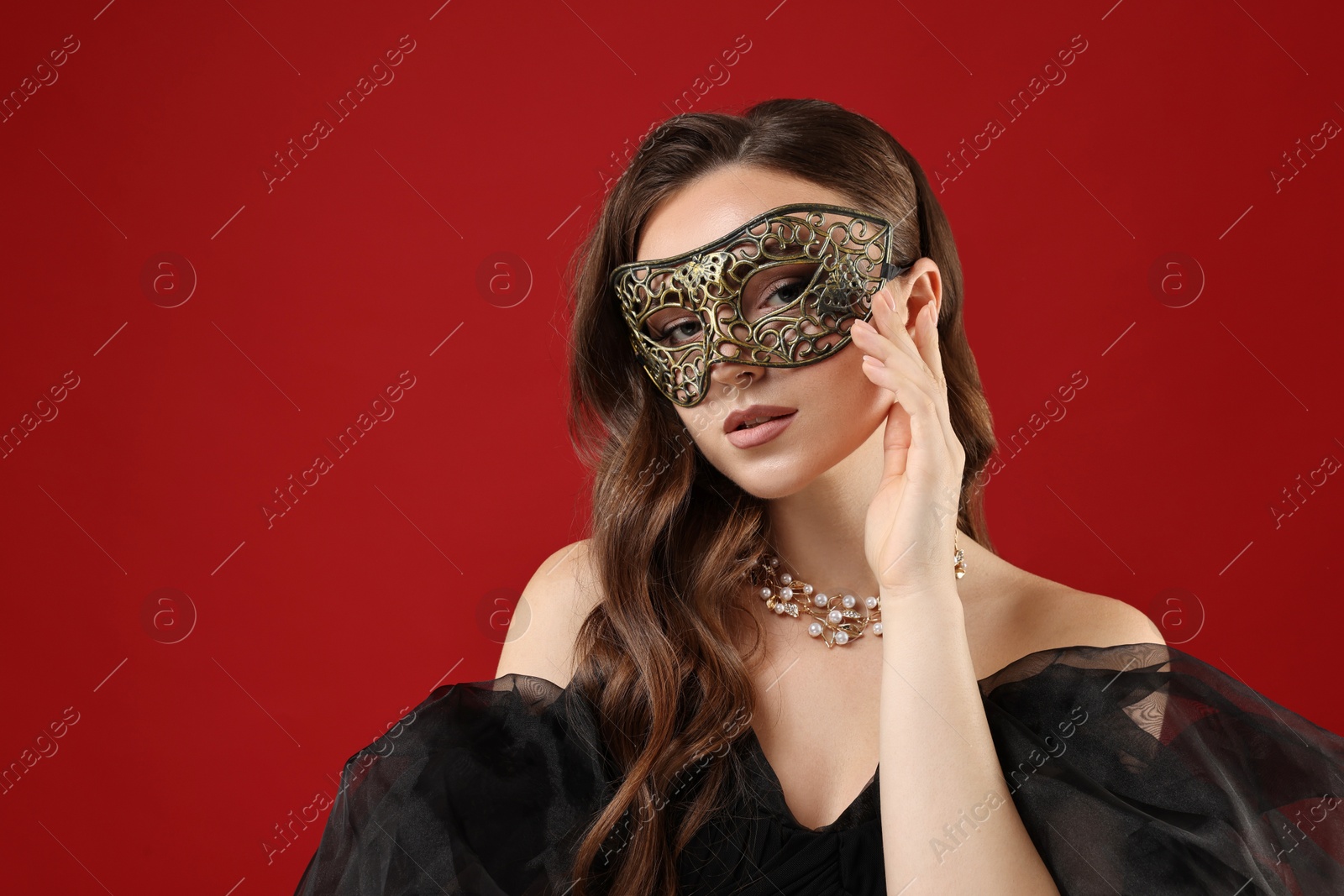 Photo of Beautiful woman wearing carnival mask on red background. Space for text