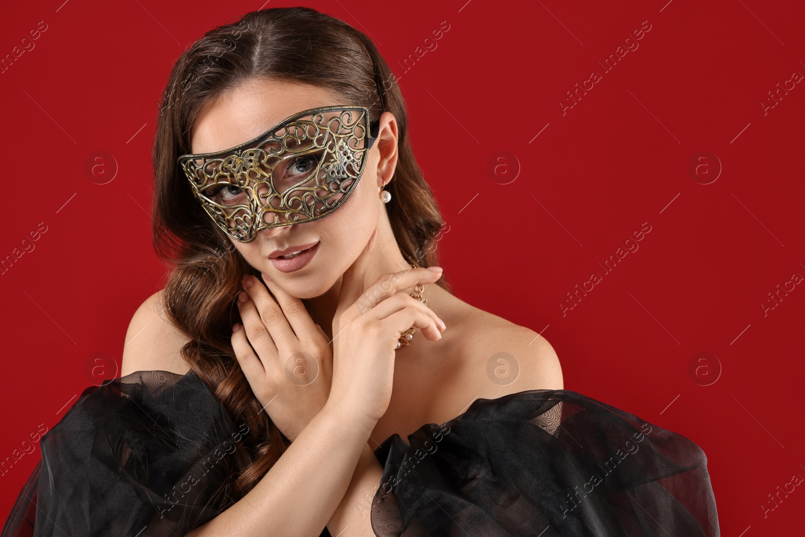 Photo of Beautiful woman wearing carnival mask on red background. Space for text