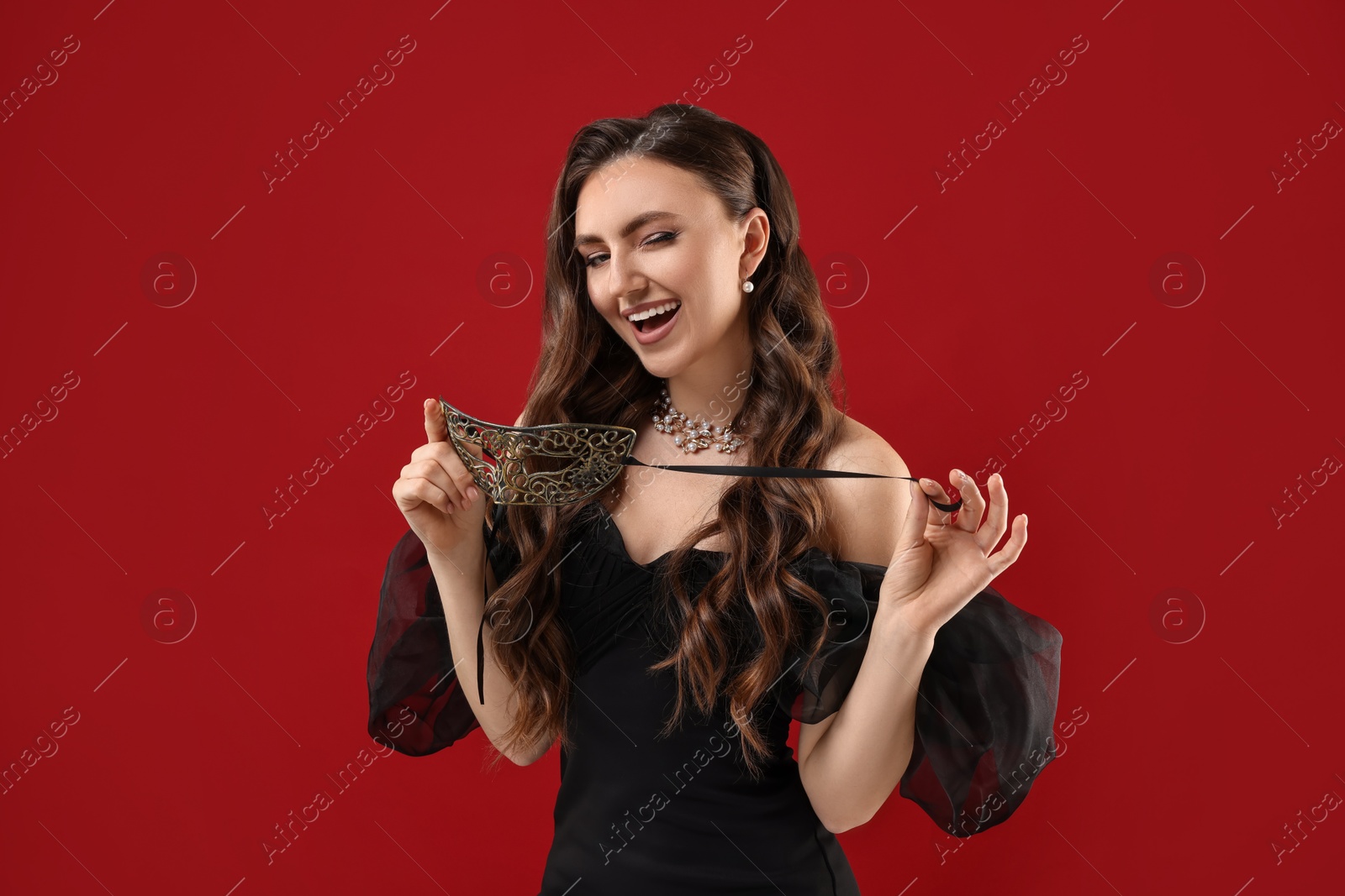 Photo of Happy woman with carnival mask on red background