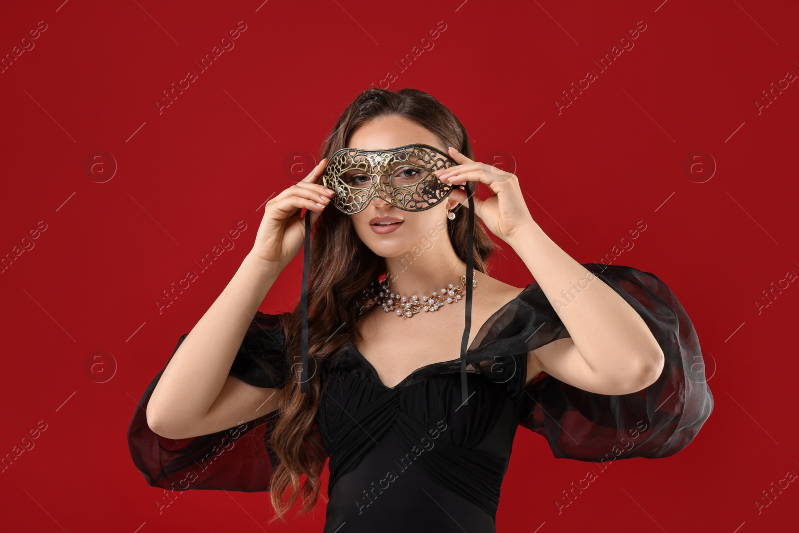 Photo of Beautiful woman wearing carnival mask on red background