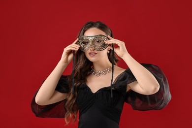 Photo of Beautiful woman wearing carnival mask on red background